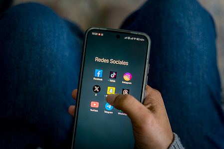 In this photo illustration, a woman is seen using social media apps Facebook, TikTok, Instagram, X, Snapchat, Threads, YouTube, Telegram, WhatsApp on a smartphone at home. Spanish Prime Minister Pedro Sánchez, announced on the 3 February a law to ban access to social media for children under 16, as Spain joins five other European countries in the “Coalition of the Digital Willing” to advance coordinated and effective regulation of social media platforms and strengthen age-verification systems across Europe.