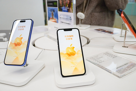 iPhones with festive wallpaper seen displayed on stands in the Apple Authorized Store at Baolong Mall.