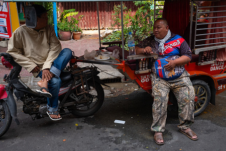 Men chat beside a remorque, a common local transportation method in the city.