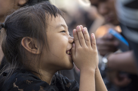 A Thai girl pays respect during the ceremony for moving the royal relics and royal funeral urn from the Royal Crematorium to the Grand Palace. Thai people bid a final farewell to their beloved departed King Bhumibol Adulyadej in an elaborate five day funeral ceremony.