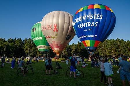 Spectators watch as hot air balloons are being prepared for launch in a park on the outskirts of Vilnius. Hot air balloon launches are popular summer activities in Vilnius and across Lithuania. Local residents and visitors often gather to watch balloons being inflated and prepared for flight, making it a common scene in the city during the warmer months.