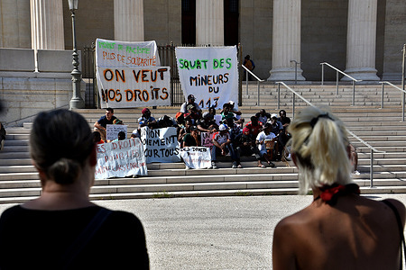 Protesters with banners sit outside the courthouse during the demonstration. Under age migrants and their supporters gathered at the courthouse of Marseille to demand their right as under age migrants to have basics needs such as a proper housing.