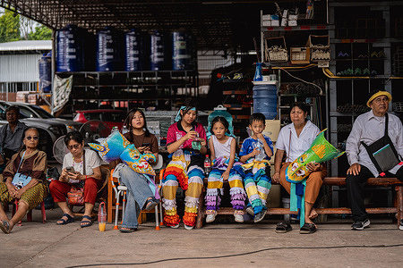 Young Phi Ta Khon performers rest with their family during a break in the parade. Locals took to the streets for the annual Phi Ta Khon festival a three-day celebration blending Buddhist and animist traditions. Rooted in the legend of Prince Vessantara, the event features ghost masks, dancing and merit-making rituals to evoke rain, fertility and spiritual protection. Once a quiet town, Dan Sai transforms into a crowded hub of tourism and festivity where elders pass down ancestral crafts with more women now joining the parade. This challenges norms in a space once dominated by men.