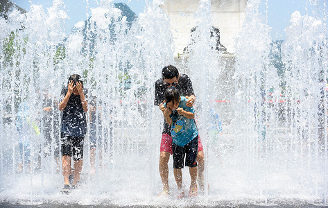 Children seen playing in water on a high temperature afternoon at the fountain in Gwanghwamun Square.