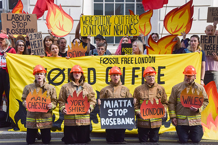Climate activists from the group Fossil Free London dressed as firefighters hold placards during a protest outside the Department for Energy Security and Net Zero (DESNZ) calling on the new Energy Secretary Miatta Fahnbulleh and the new UK Prime Minister Andy Burnham to stop the Rosebank oil and gas field in the North Sea.