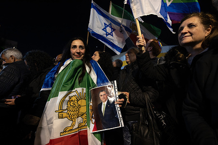 An Israeli woman is wrapped in the old Iranian flag of the former Shah, Reza Pahlavi, with the Israeli flag in the background. A rally in support of protesters in Iran was held in the city of Holon in central Israel, drawing tens of thousands of Israelis, including social activists and Iranian immigrants. Participants displayed signs reading “For Freedom” and “For Iran,” and some carried portraits of Reza Cyrus Ali Pahlavi, the son of Iran’s former king. Many attendees said the rally was meant to express solidarity with the Iranian people and hope for a future in which Iran gains freedom and renews peaceful relations with Israel.