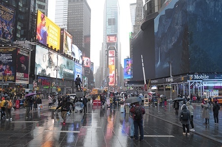 People hold umbrellas and walk in the rain in Times Square, Manhattan, New York City.
