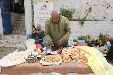 Palestinian man displays various types of bread baked over a wood fire on the main street in the Rafidiya neighborhood during the "Salt of the Earth" and Palestinian Heritage Exhibition. Baking bread over a wood fire is a long-standing Palestinian tradition.