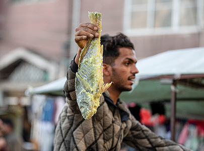 A Palestinian street vendor holds salted fish called "Al Fesikh" in a local market in Khan Yunis, southern Gaza Strip, ahead of Eid al-Fitr, which marks the end of the holy month of Ramadan.