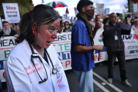 Protesters, one her face covered with fake blood march along the Embankment supporting health workers for Palestine during the rally. Supporters of Palestine gather in London and demand a change in policy from the Burnham government. They insist the UK stops selling arms to Israel where they believe they are being used against Palestinians in Gaza and elsewhere. They commemorate the three years of the recent war but also highlight the Palestinians plight for the last 70 years.