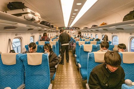 Travelers are seated inside a Shinkansen high-speed train carriage, a key mode of intercity transportation known for its speed and efficiency across Japan. The Shinkansen, or bullet train, is Japan’s high-speed rail network known for its punctuality, efficiency, and smooth ride. It connects major cities across the country at speeds of up to 300 km/h, making long-distance travel fast and reliable.