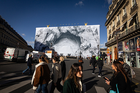 People seen passing in front of Opera Garnier with facade of JR artwork at Place de l'Opera. The french artist JR decorated the facade of the Opéra Garnier to present Act II of his performance "Chiroptera". "Dans la caverne" will be presented to the public on November 12th at the Opéra Garnier in Paris.