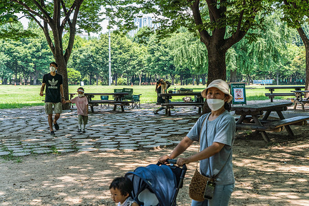 People wearing facemasks are seen walking in the park in Seoul as a heatwave blankets the country.