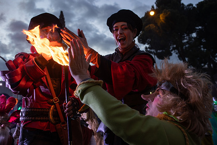 A performer warms her hands with the flames of other performers' torches. during the traditional Three Kings Parade, held in celebration of Epiphany, through the main streets of downtown Madrid.