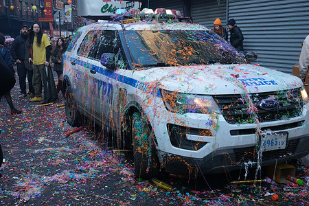 A police car is co vered with silly spray and confetti by New Years revelers. The New Year's celebration in Chinatown where the dragon puppets visit each store along the streets to spread good luck.  Firecrackers are used during the Lunar New Year to ward off evil spirits.