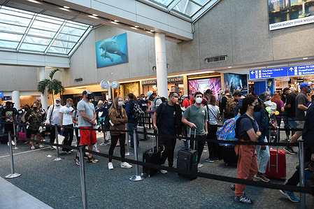 Spring break passengers wait in a TSA security line at Orlando International Airport. While COVID-19 face masks are still required, crowds have increased over last year.
