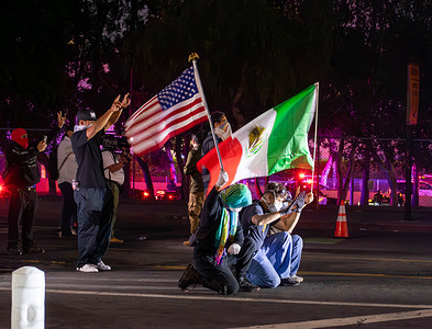 Protestors with US and Mexican flags in front of a line of police. These photos were taken during the Anti-ICE protest in Los Angeles this week. The daytime images were captured before curfew hours, while the nighttime shots were taken during the curfew.