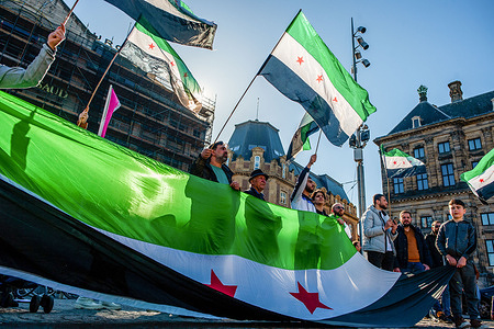 Syrian people are seen holding a big Syrian flag during the demonstration. In March 2011, after four decades of dictatorship, the Syrian people rose up peacefully to demand democracy and dignity. The regime of Bashar al-Assad crushed that uprising with force, triggering an international war that has killed more than 500,000 and driven 12 million from their homes. Eleven years after, In Amsterdam, Syrian people gathered at the Dam square to keep demanding for their legitimate rights, freedom, and a peaceful Syria.