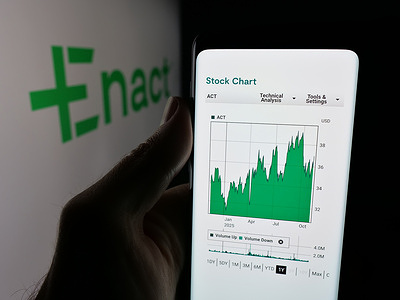 In this photo illustration, a person is holding a smartphone with the webpage of US mortgage company Enact Holdings Inc. on screen in front of logo.