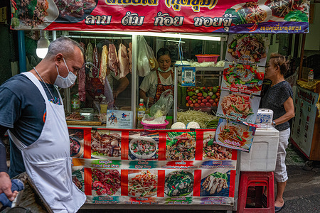 A porter walks past a food stall at Pratunam Market, one of the largest and busiest wholesale clothing markets in Bangkok.