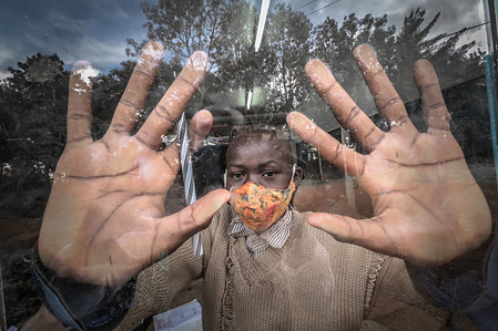 A young boy poses for a photo through a classroom window with his face mask following the reopening of schools after a nine months period of no school due to the coronavirus pandemic.