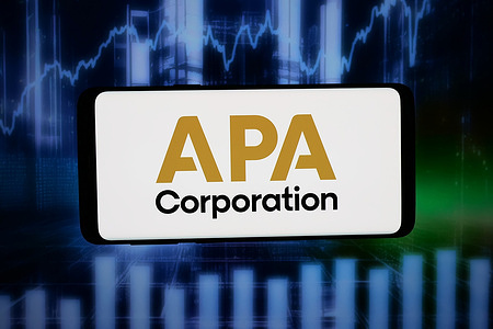 In this photo illustration, the logo of US petroleum company APA Corporation is displayed on a smartphone in front of abstract background on computer screen.