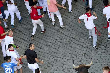 Runners race in front of a bull through the streets of Pamplona during the San Fermín 2025 festivital, and the bulls are from Alvaro Nuñez ranch.