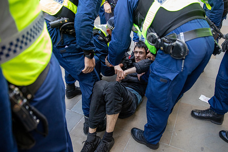 Members of the Metropolitan police's Tactical Support Group (TSG) arrest a member of the vegan Protest group, RAGE during a demonstration outside the Louis Vuitton store on New Bond Street London. Vegan activists from RAGE staged a protest outside the Louis Vuitton store on New Bond Street. Disguised as shoppers, some entered and revealed signs before being removed by staff and security. Police were called as tensions rose, leading to an arrest outside the store.