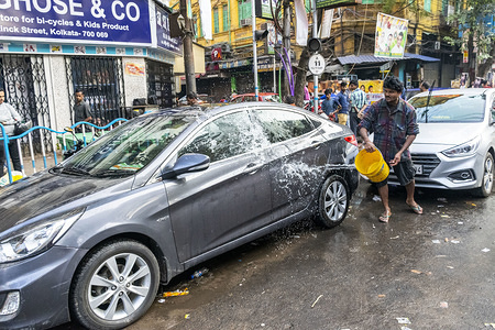 A man washes a car on a roadside in Kolkata.