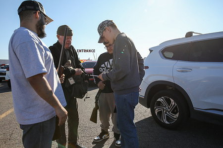Gun enthusiasts gather on the parking lot of the Crossroads of the West gun show, in Phoenix.
