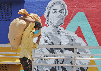 A man carrying a sack on his head walks past a graffiti of coronavirus warrior in Mumbai.
Mural depicts a nurse as one of the many corona warriors who have worked throughout the lockdown, exposing themselves to the risk of infection. It is the expression of what every citizen is thankful for the efforts of essential service providers in the face of rising covid-19 cases.