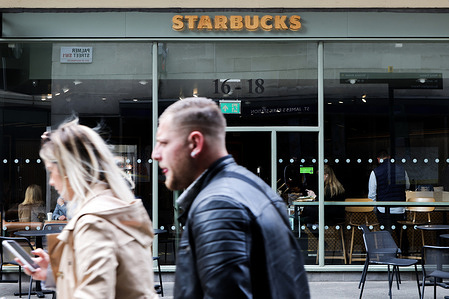 A couple walks past a branch of Starbucks.