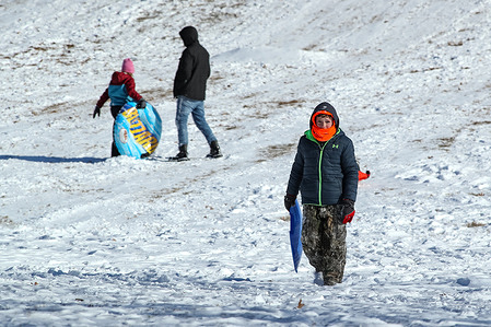 Children take advantage of a day off from school to go sledding after several inches of snow fell.