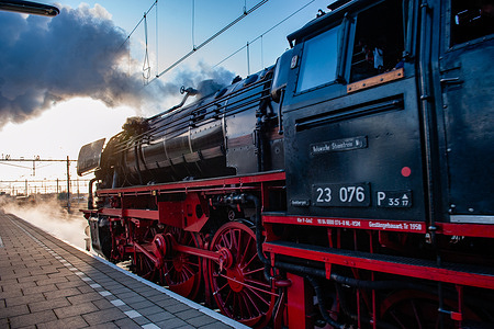 A view of the train leaving a huge cloud of steam. For the past three years, the Christmas Express, a historic steam train, has been running between Arnhem and Nijmegen around Christmas Day. Conductors in period costume were waiting to assist the people with boarding. These historic trains are still heated, traditionally, with steam from the large steam locomotive. The trains were running between the two stations throughout the weekend.