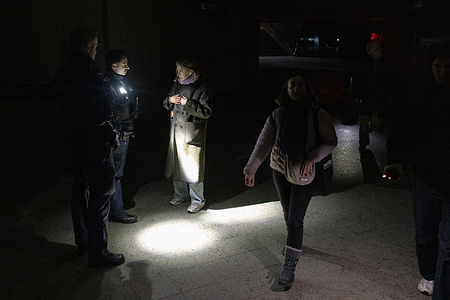 A woman speaks with police officers during a power outage at Wannsee S-Bahn station as large parts of southwest Berlin remain without electricity. The blackout followed a sabotage attack on electrical cables at a bridge crossing the Teltow Canal, disrupting power to tens of thousands of residents as well as transport infrastructure and public services. Police are patrolling affected areas and assisting residents while utility crews continue restoration work. Temporary emergency measures remain in place as repairs proceed.