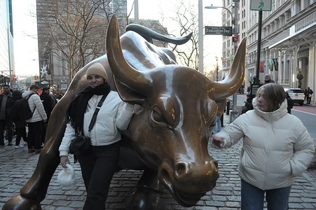 People take photos by the "Charging Bull" statue in the Financial District in Manhattan, New York City.