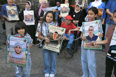 Chained Palestinian children seen holding up pictures of their fathers imprisoned in Israeli jails. They also demanded to be allowed to visit their people in Israeli prisons. The mothers of the prisoners said that the Israeli government has prevented them from visiting their sons since October 7 2023 when Hamas attacked Israeli settlements.