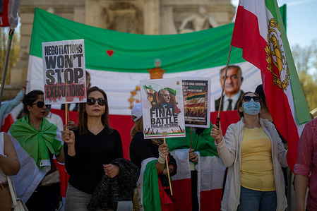 Iranian protesters hold placards in front of a large Iranian flag with portrait of Reza Pahlavi, the Crown Prince of Iran residing in the US during a rally. Iranian residents in Madrid's Plaza de España held a rally to demand an end to the abuses committed by the theocratic regime of the ayatollahs against the people of Iran.