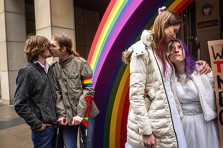 Two HomoKomando activists kiss while others share a look together. LGBTQ+ activists and supporters speak to the press before the Polish Supreme Administrative Court rules on a landmark human rights case concerning same-sex marriage. In a huge victory for LGBTQ+ rights, the court rules that foreign same-sex marriages must be recognized in Poland and that this does not violate the Polish constitution. Prior to the ruling, activists of the HomoKomando group, including founder Linus Lewandowski, speak to the press.