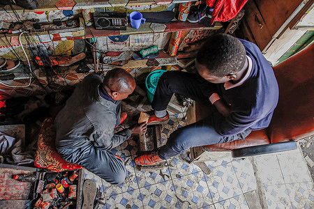 Daniel Mwangi, a local cobbler cleans his customer's shoes at his shop in Kibera Slum. Mr. Paul Mwangi works as a shoe cobbler and has been serving residents from Kibera Slum with shoe cleaning, and repair services, including selling brand-new shoes to locals since 2010. 
Working from his mini street shop has been a journey fraught with challenges, including experiencing tribalism from locals due to being the only Kikuyu individual present. It is important to note that the Kikuyu people belong to the Northeastern Bantu branch.