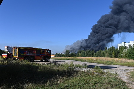 Smoke rises from a fire at a large warehouse storing car tires and wheels following a Russian strike in the Bucha district. Drones hit a warehouse and home, while others were intercepted. The Ukrainian Air Force had earlier detected ballistic missiles heading towards the Ukrainian capital.