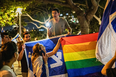 A religious youth shouts at a woman covering his sign with a pride flag during a demonstration against the judicial reform.
