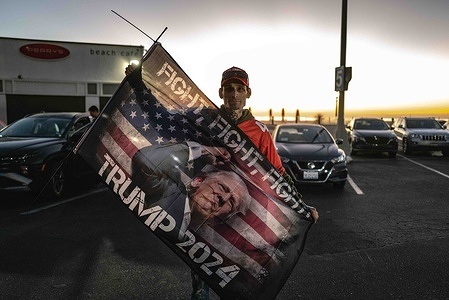A large, enthusiastic crowd of Trump supporters gathers on Santa Monica Beach at sunset, waving American flags and cheering in celebration of the election results. The sky is painted with warm orange and pink hues, adding to the festive ambiance. Santa Monica Beach saw a gathering of Trump supporters celebrating his projected win in the 2024 U.S. presidential election. The event drew an enthusiastic crowd, as people waved flags, chanted slogans, and shared in the excitement. Organized spontaneously through social media, the celebration saw a mix of families, young supporters, and longtime backers who came together to mark the moment.