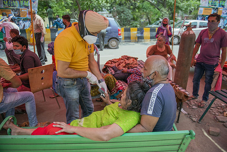 A health official reads the oxygen level of covid-19 patient during free oxygen Langar outside Gurudwara Sri Guru Singh Sabha. 
India faces shortage of medical oxygen. In such circumstances, an NGO known as Khalsa Help International helps Covid-19 patients by offering them free oxygen. In the last 24 hours, India recorded 3,68,147 new Covid19 cases with 3417 Deaths.
