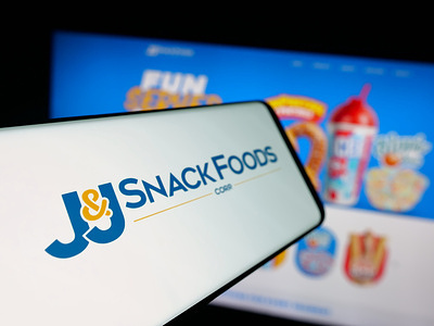 In this photo illustration, a smartphone with the logo of US food company JJ Snack Foods Corp. is seen on screen in front of website.