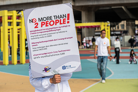A Labour Department staff member holds a sign alerting foreign domestic helpers about COVID-19 social distancing rules. 
With a recent increase in cases in Hong Kong, the government has increased testing and furthered limits social gatherings to combat the disease.