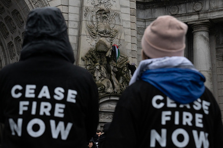 Two demonstrators watch on as a man drapes a Palestinian flag over a marble statue. Demonstrators of Jewish Voice for Peace block the western entrance of the Manhattan Bridge for several hours, calling for a longlasting cease-fire in Gaza. The group held a similar action, a sit-in, in Grand Central Terminal at rush hour in October.