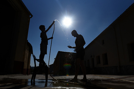A child holds a pipe of water over a man to cool off in Rebollo de Duero, north of Spain, where temperatures have reached 38º degrees Celsius in the afternoon hours.
Spanish's weather agency AEMET said that several provinces are with an orange or yellow heart warning alerts for today, July 11, with temperatures reaching up to 41 Celsius degrees during the day.