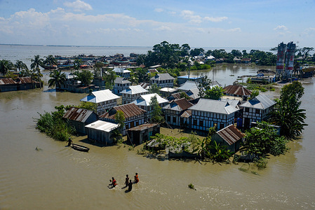 People wade through a submerged road with flood waters all around.
The flood situation is worsening in Munshiganj. Due to the heavy rain, the water level of the Padma River has risen which resulted in a flood. At least 1.5 million people have been affected, with homes and roads in villages flooded. Flood Forecasting and Warning Centre (FFWC) officials have reported, the flood situation in 15 northern and central districts due to the rise in the water level of the main rivers.