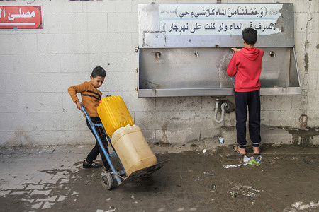 Palestinian children fill up water bottles in the Al-Shati refugee camp, west of the Gaza Strip. Palestinian refugees in the Gaza Strip have criticized the United Nations (UN) decision to cut aid and services provided to them. The majority of Gaza residents are refugees who were expelled from their cities and villages when the Israeli regime was established in 1948.